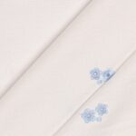 Tessuto Piquet di Cotone Ricamato - Fiore Celeste Fondo Bianco - Mezzo Metro